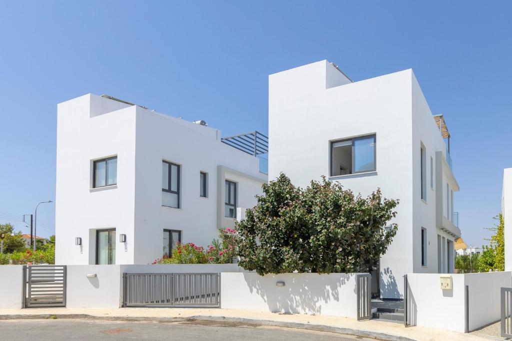 a white building with a tree in front of it at Seaside Emerald in Paralimni