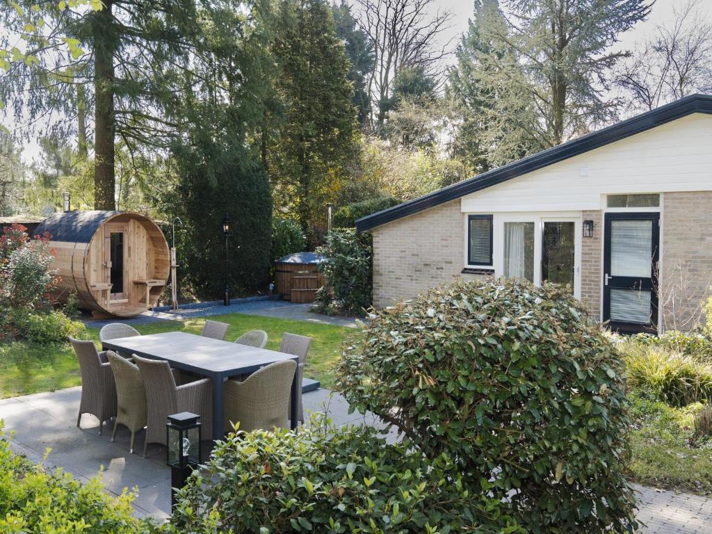 a patio with a table and chairs in a yard at Holiday Home Voorthuizen near De Veluwe in Voorthuizen
