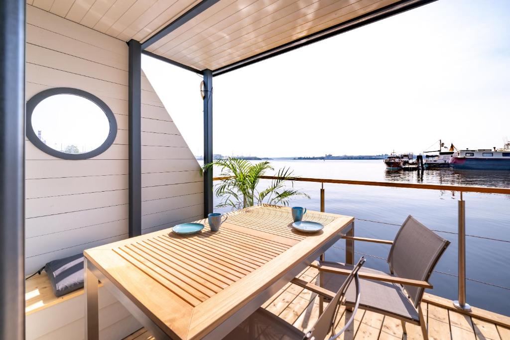 a deck with a table and chairs on a boat at Hausboot Schatzkiste in Fehmarn