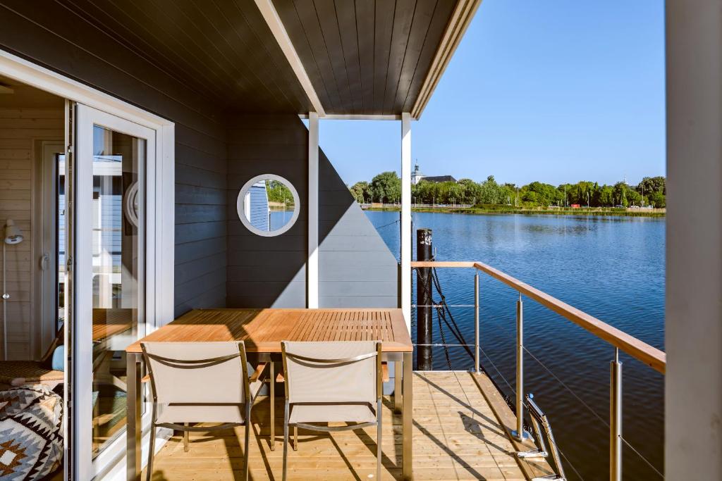 a deck with a table and chairs on a boat at Hausboot TreibGut in Fehmarn