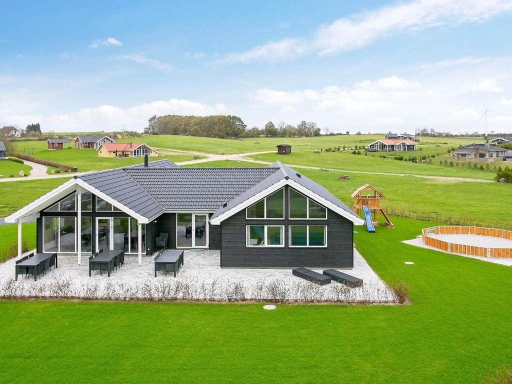 a black house with a playground in a field at 18 person holiday home in Faaborg in Fåborg