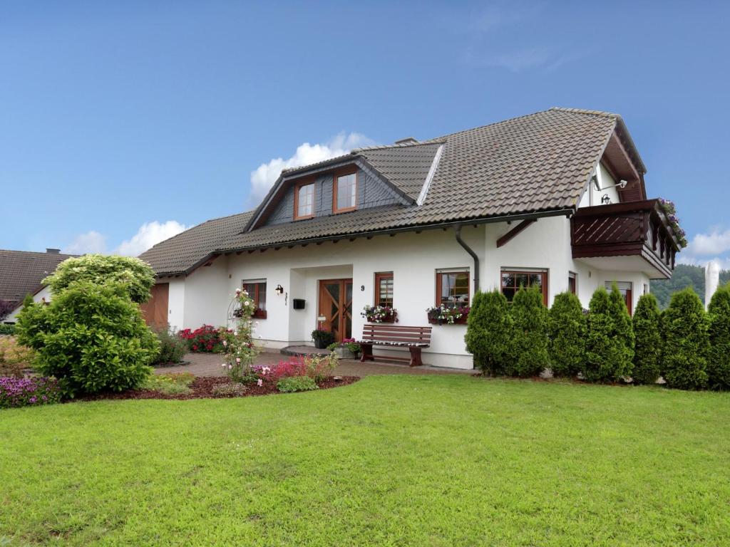 a white house with a bench in the yard at Ferienwohnung im Sauerland in Medebach
