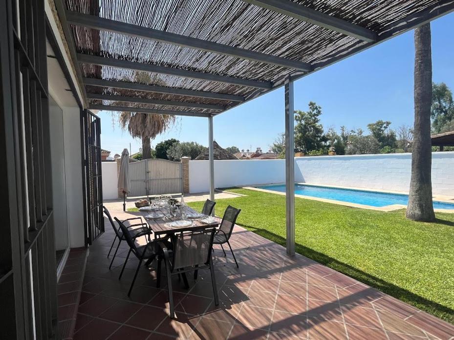 a patio with a table and chairs and a pool at Sunset Palm in El Puerto de Santa María