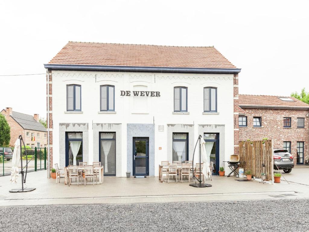 a white building with tables and chairs in front of it at Glabbeek Family Retreat Home in Bunsbeek
