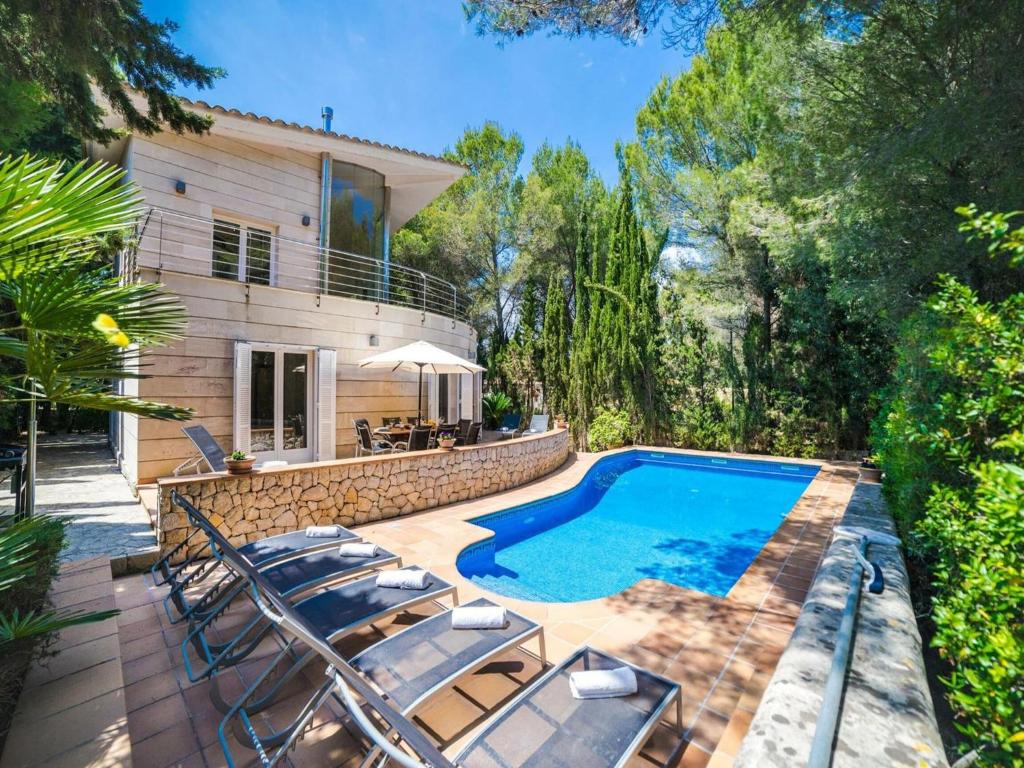 a swimming pool with chairs and a house at Villa in Alcúdia near Sandy Beach in Alcudia