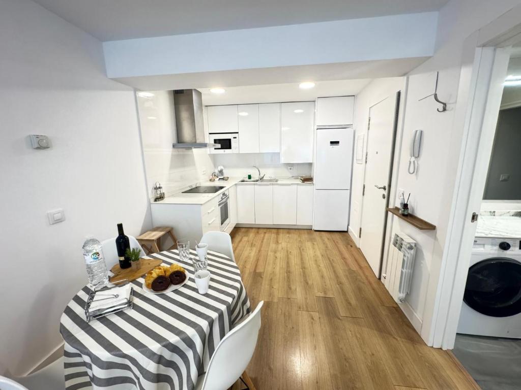 eine weiße Küche mit einem Tisch und weißen Geräten in der Unterkunft RIOJALAND 1B precioso alojamiento en el centro de Lardero in Lardero