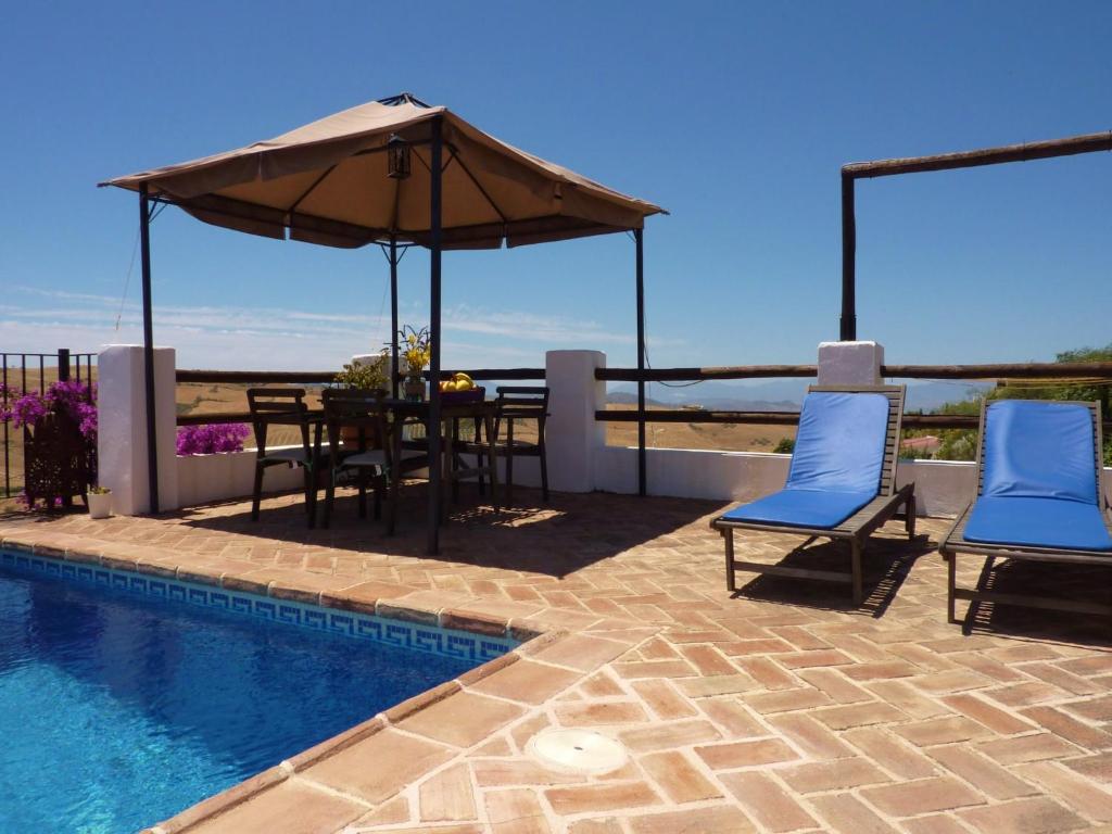 Un patio con una mesa y sillas y una sombrilla. en Countryside Villa Escape, en La Joya