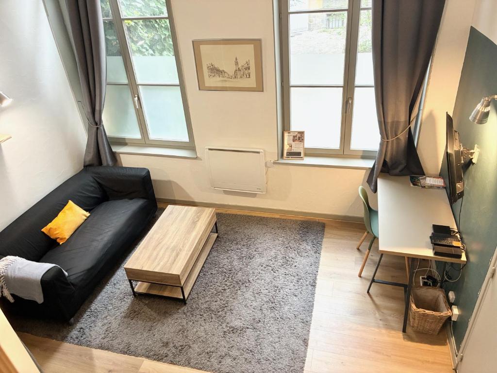 a living room with a black couch and a table at Appartement Grand Place de Lille - 2 voyageurs in Lille