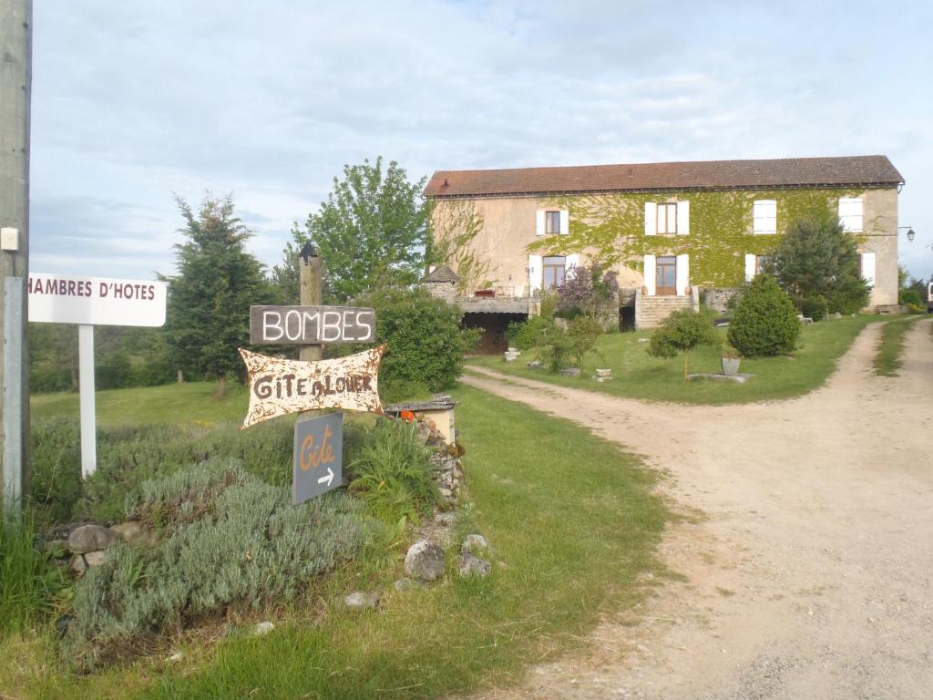 ein Haus mit einem Schild vor einer unbefestigten Straße in der Unterkunft chambres du Domaine de Bombes in Mostuéjouls