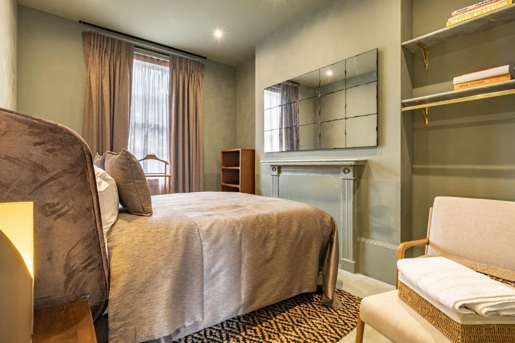 a bedroom with a bed and a chair and a window at The Rokxy Townhouses & Residences - Kings Cross in London