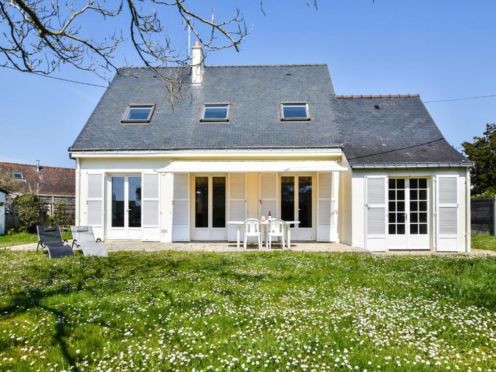 a white house with a table and chairs in a yard at Beachside Brittany Escape in Pénestin