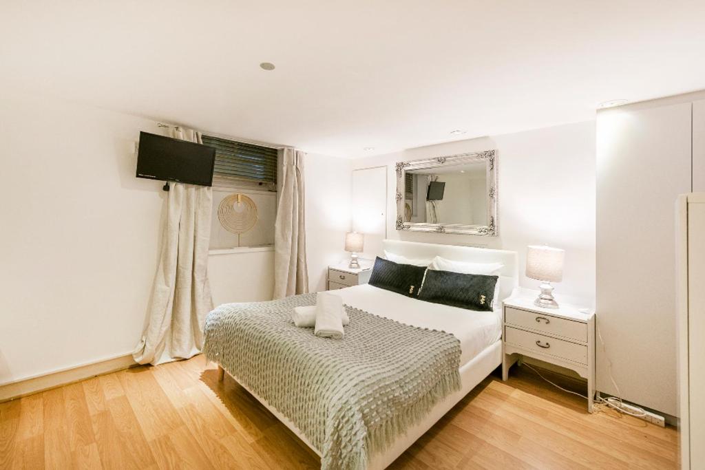 ロンドンにあるPrivate rooms with shared bathrooms and a top floor studioのベッドと鏡のある白い寝室