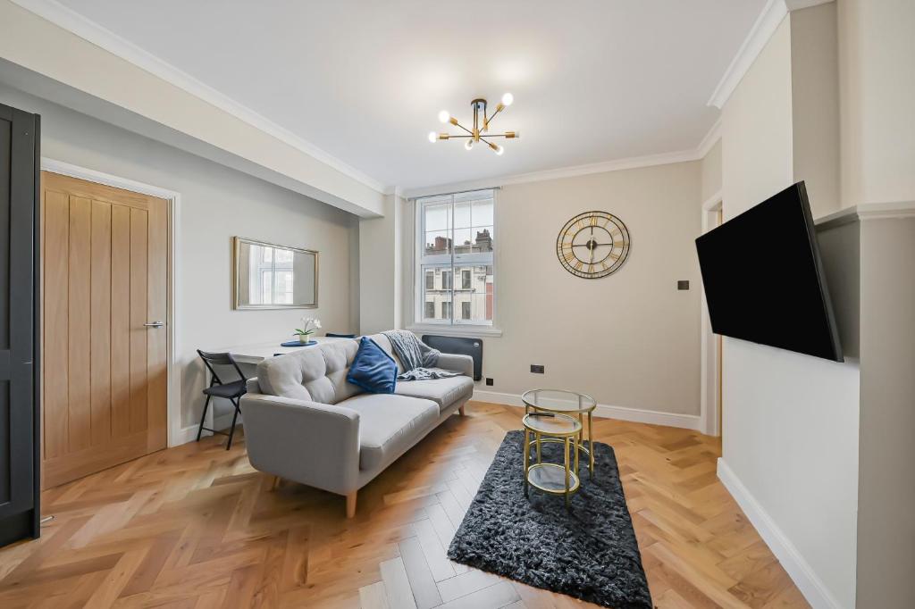 a living room with a couch and a tv at Cambridge Court Central Flats in London