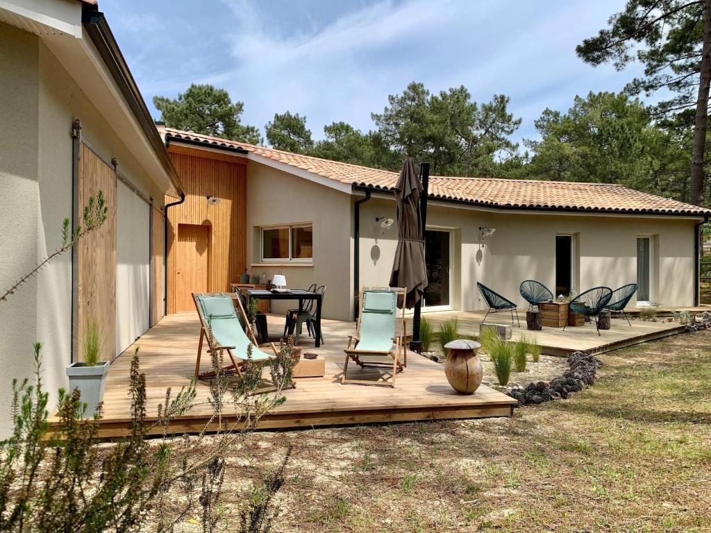 une terrasse avec des chaises, une table et une maison dans l'établissement Chic Retreat by the Dunes, à Carcans