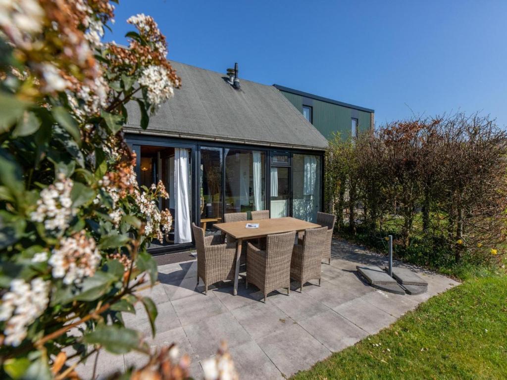 a patio with a table and chairs in front of a house at Holiday Home near Beach with Pool Access in Burgh Haamstede