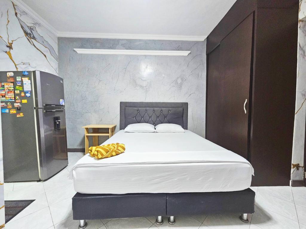 a bedroom with a large white bed and a refrigerator at Apartahotel Casa Blanca in Medellín
