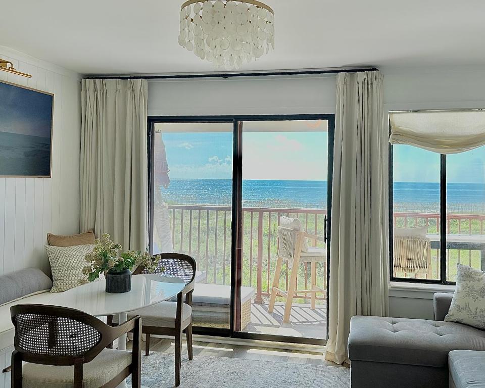 a living room with a table and a view of the ocean at Direct Luxury Oceanfront - On The Beach! Amazing Sunrises, 2 Pools & Bar! in Hilton Head Island