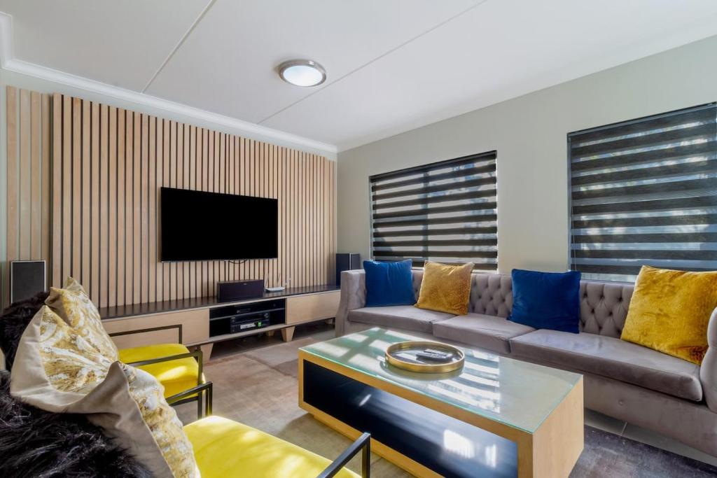 Una sala de estar con un sofá y un televisor. en #AlimamaSpaces The Manson Umthunzi View, en Vosburg