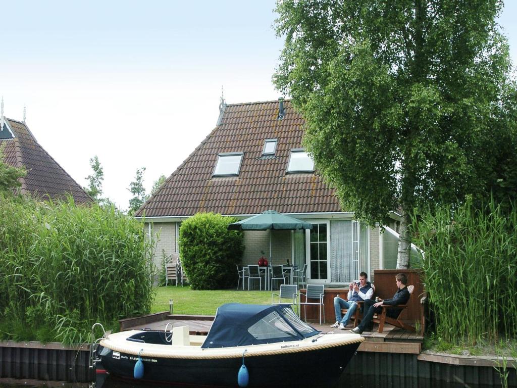 two people sitting in a boat in front of a house at Wellness aan het Water in Earnewoude in Earnewâld