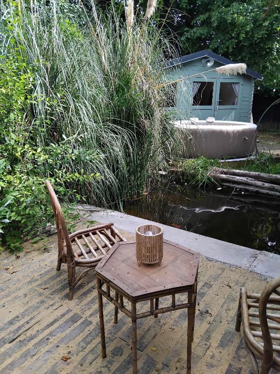 a table and chairs on a dock with a boat at La cabane de Mimi la Sardine in Laigné-en-Belin