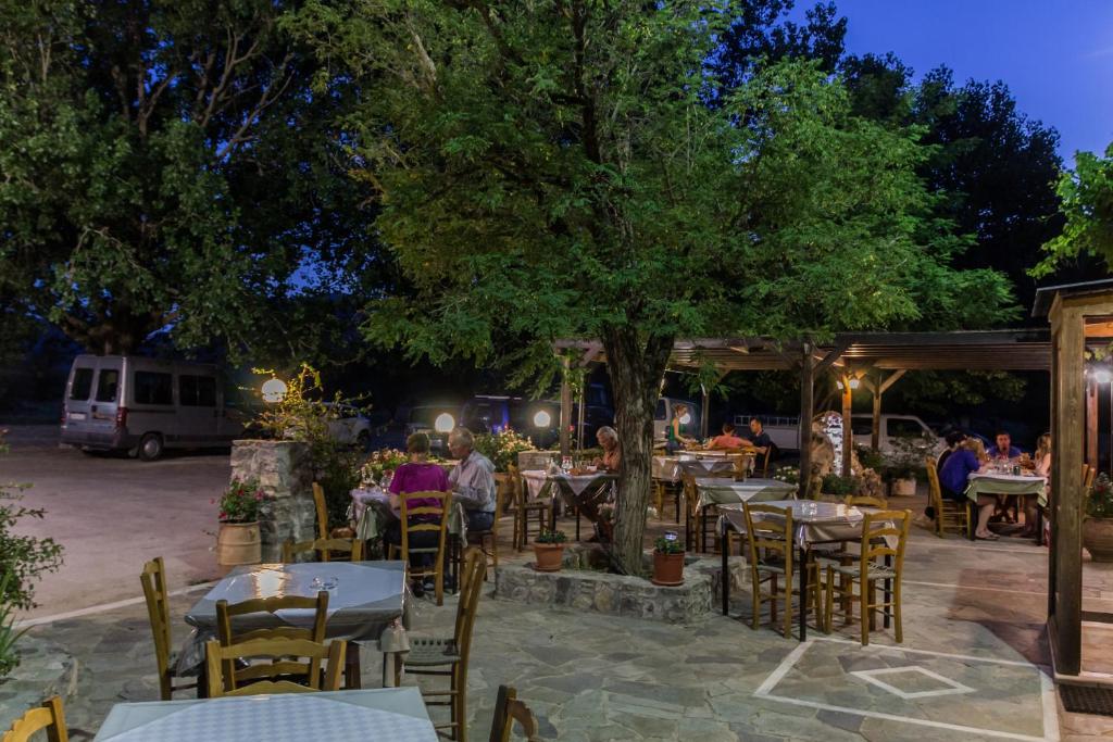 un gruppo di persone seduti ai tavoli sotto un albero di Neos Omalos Hotel a Omalos