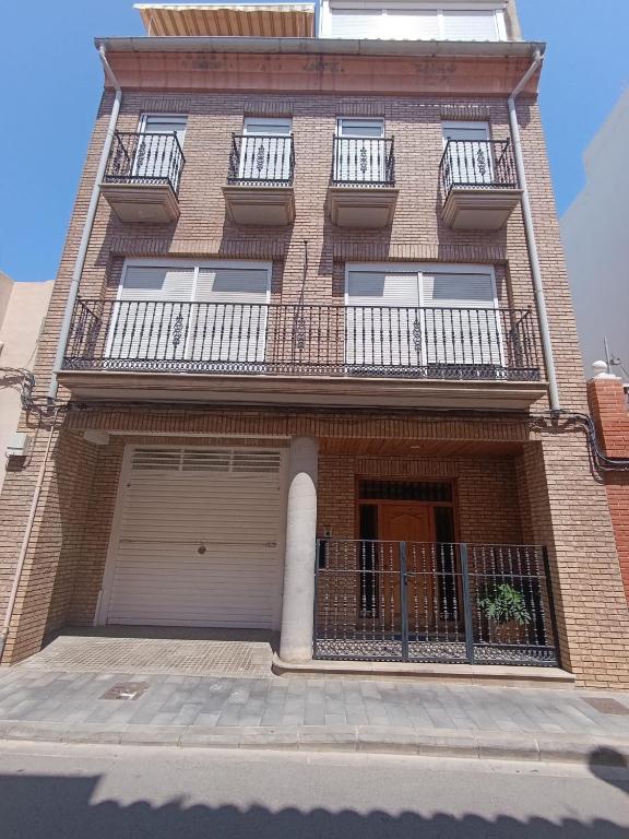 a large brick building with a garage and balcony at First Floor Casa Privee - Two bed Beach Terrace & Balconies in Puerto de Sagunto