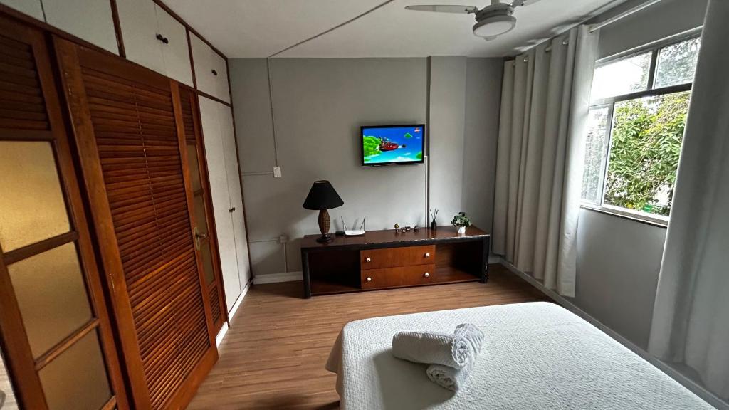 a bedroom with a bed and a tv on the wall at Apartamento completo no Centro de Nova Friburgo in Nova Friburgo