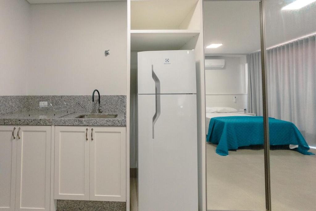 a kitchen with a white refrigerator and a bedroom at Seu apê ideal te espera! CA1306 in Maringá