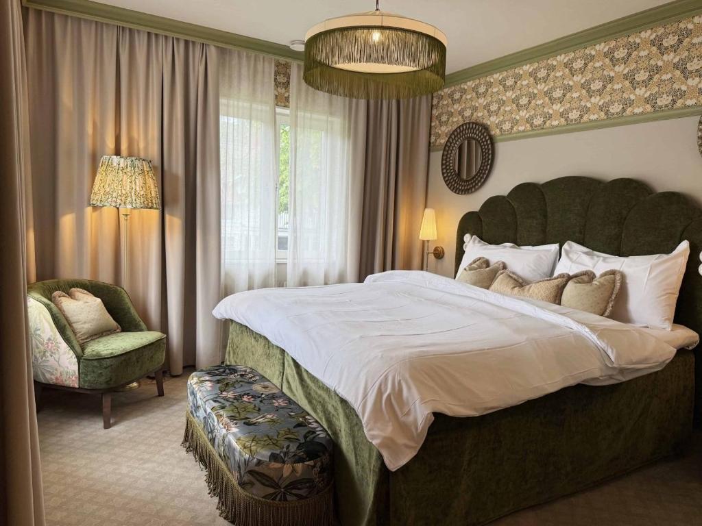 Un dormitorio con una cama grande y una silla. en Karstorp Säteri – Hotell och Konferens, en Skövde