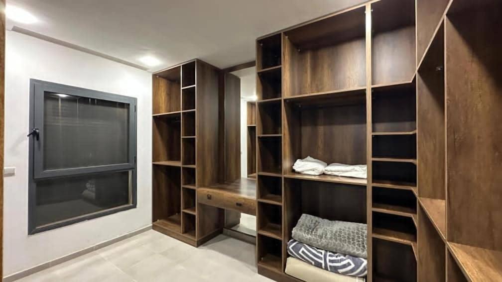 a walk in closet with wooden shelves and a window at villa pools bbq lounge in Oujda