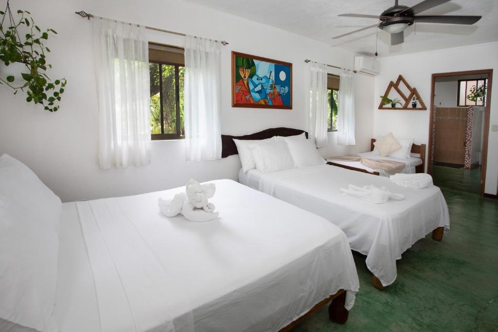 two beds in a room with white walls and green floors at Villas Jacquelina in Quepos