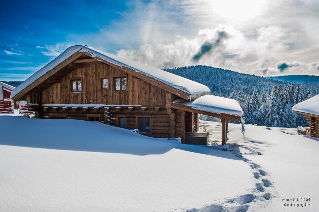 a log cabin covered in snow with the sun in the background at Chalet Harmony, Liézey - Gérardmer 9p - Spa in Liézey