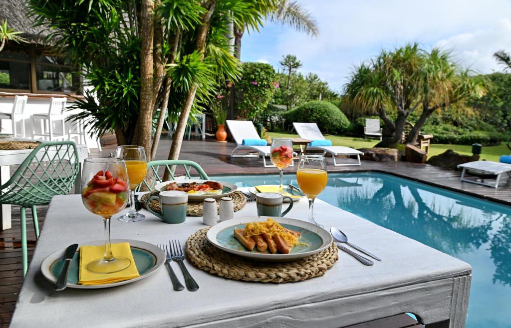 a table with food and drinks next to a pool at BonBini Guest House in St Francis Bay