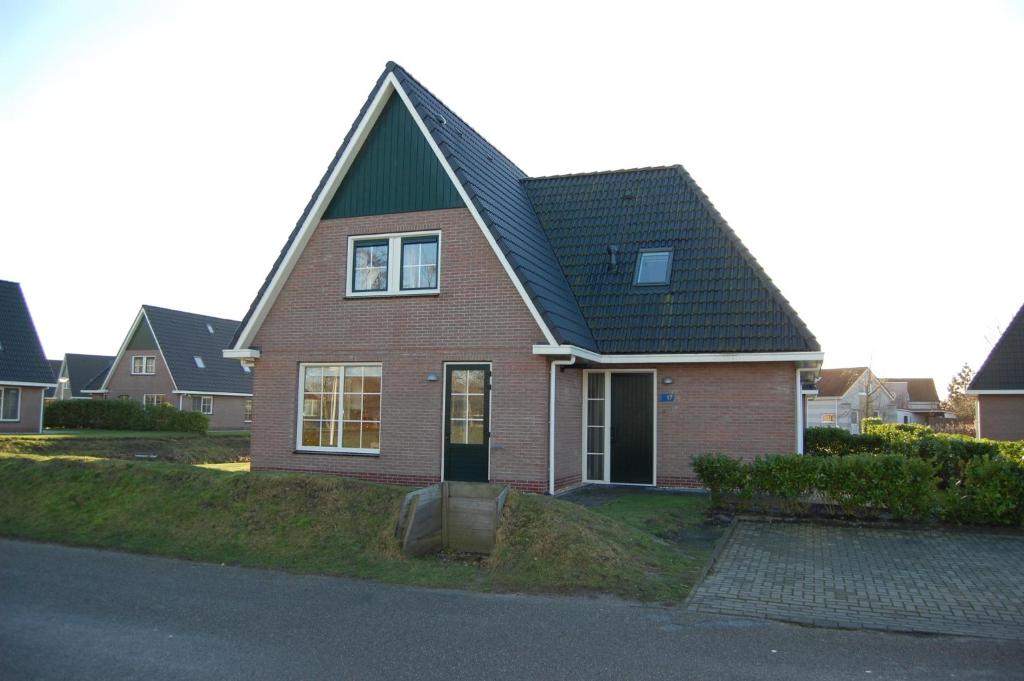 a brown brick house with a green roof at Beachvilla Royaal Classic met Sauna - 10 personen in Holle Poarte