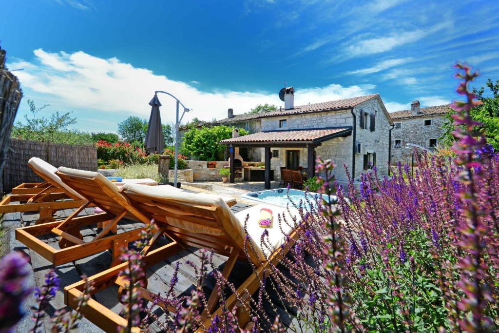 einen Garten mit einem Stuhl, einem Haus und Blumen in der Unterkunft Holiday Home Gašparini in Višnjan