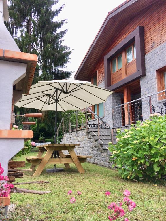 a picnic table with an umbrella in front of a house at Apartamento Casa Maru in Santillán