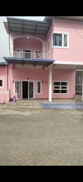 a pink house with a balcony on top of it at Villa Brastagi Gunung Mas Blok A1 in Berastagi