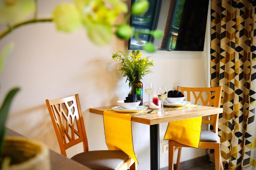 Intimate dining table set for two with yellow runners, wine glasses and floral centerpiece.