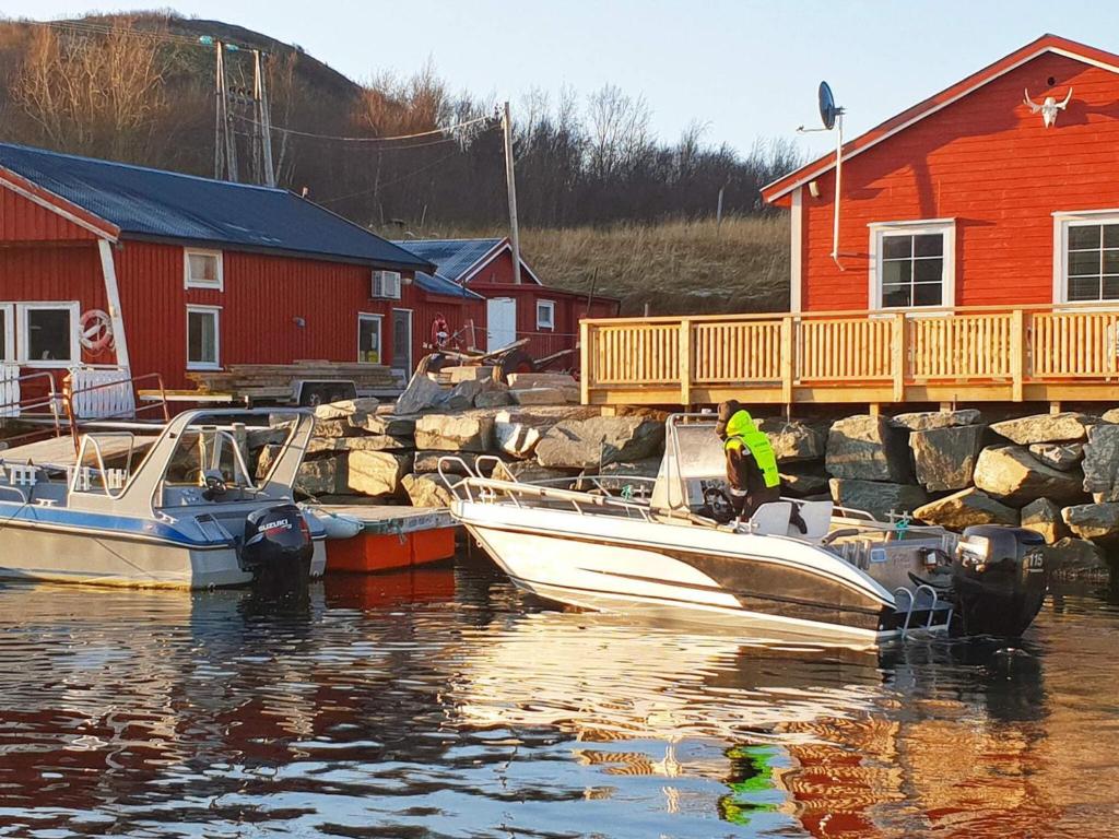 two boats are docked in a marina next to a red house at 6 person holiday home in Oksvoll in Oksvoll