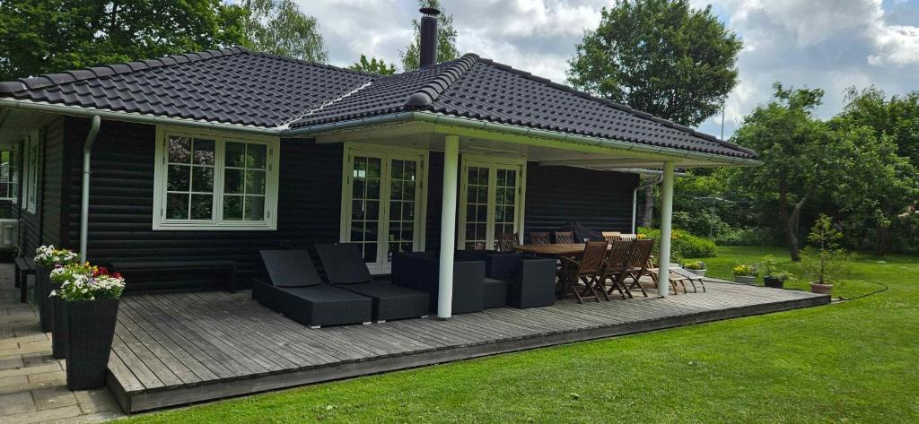 czarny dom z tarasem ze stołem i krzesłami w obiekcie Cozy Cottage Just 300 M From Høve Beach w mieście Asnæs