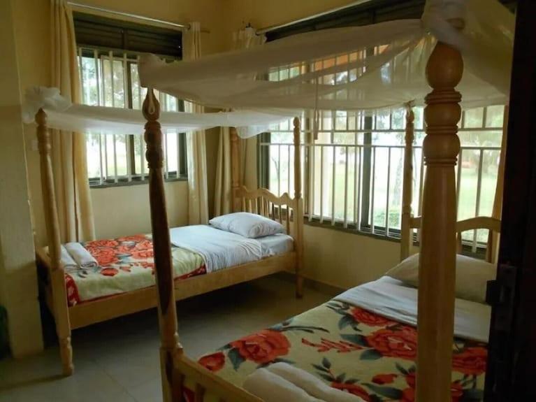 a bedroom with two beds and two windows at Kalangala Pearl Resort Beach in Kalangala