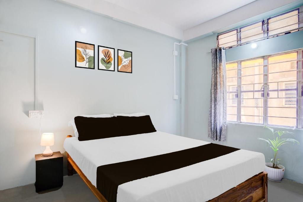 a white bedroom with a bed and a window at Hotel O Sunrise Guest House in Guwahati