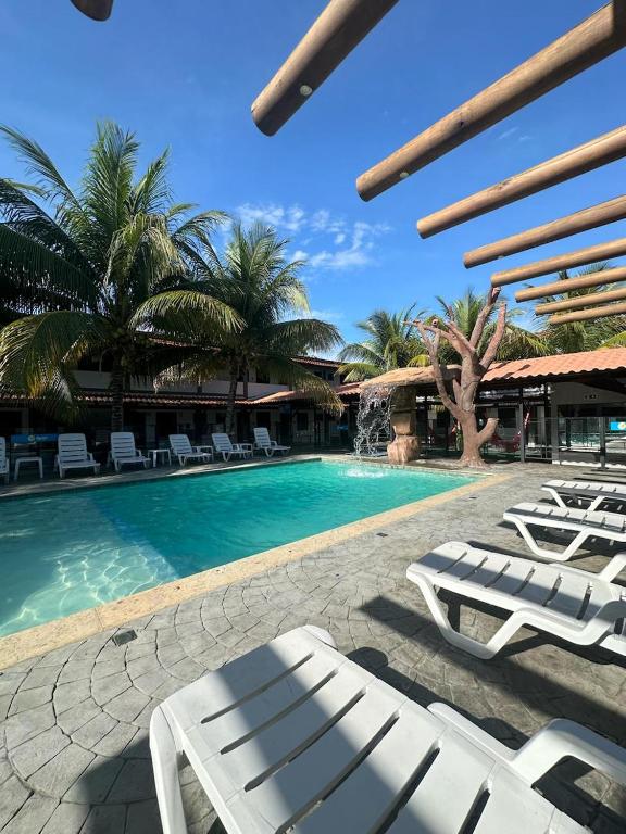 una piscina con tumbonas blancas junto a un complejo en Pousada Aguas Quentes, en Barra do Garças