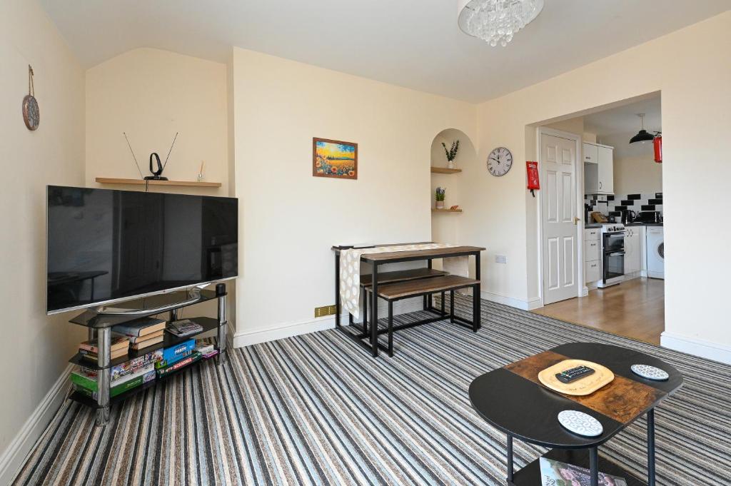 a living room with a flat screen tv and a table at Hunstanton Holidays Flat 3 with seaview in Hunstanton