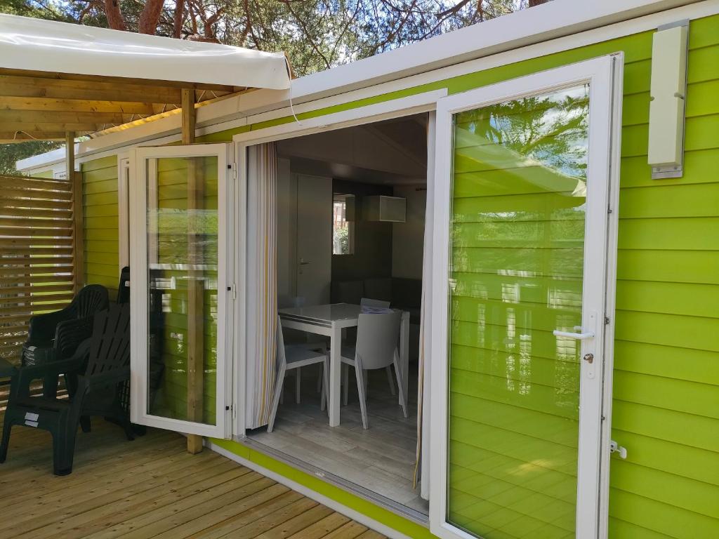 eine Glasschiebetür an einem Gewächshaus mit einem Tisch in der Unterkunft mobil home premium 6 personnes très confortable climatisé in Montagnac