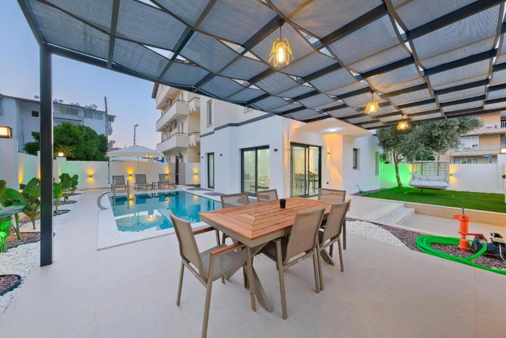 a patio with a wooden table and chairs and a pool at The B HOUSE in Fethiye