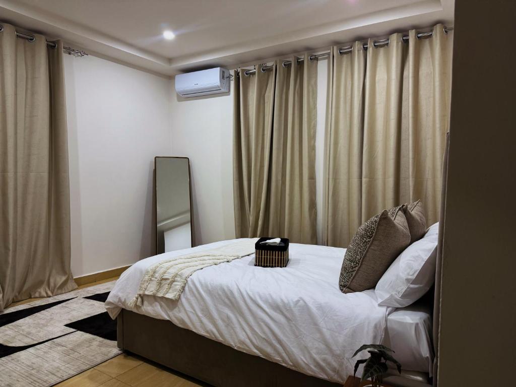ルサカにあるNiza Homes, Luxury Kalundu Escapeのベッドルーム1室(ベッド1台、鏡、カーテン付)