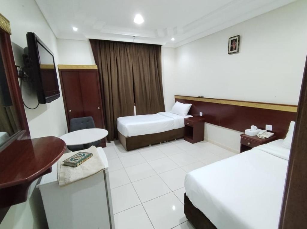 ein Hotelzimmer mit zwei Betten und einem Fernseher in der Unterkunft تولب الفضي in Az Zahrāʼ