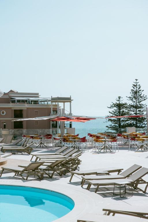 a group of lounge chairs and tables and a swimming pool at Las Vegas Resort Malta in St. Julianʼs
