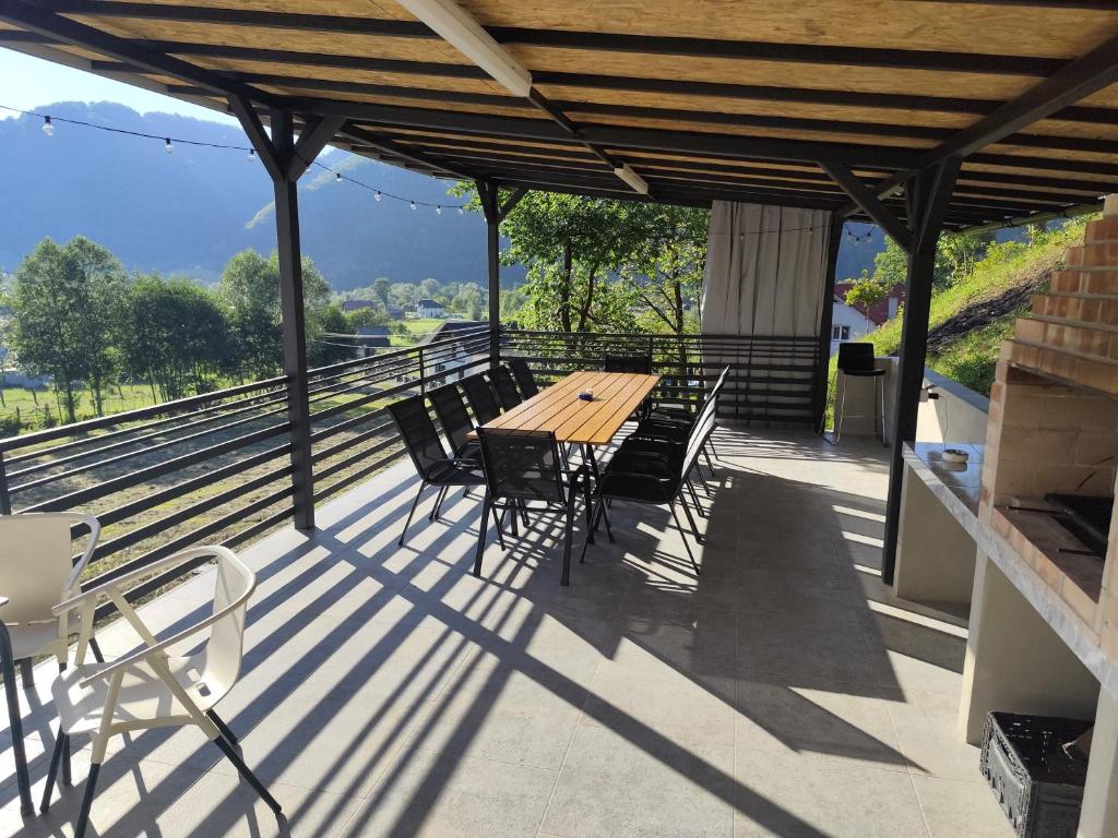 a wooden table and chairs on a deck with a view at CasaNatur in Leordina